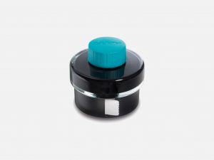 a 50ml glass bottle of lamy t 52 turquoise ink and built in blotting paper roll on a grey background